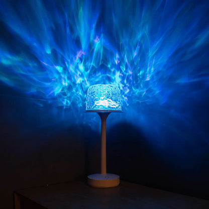 A matte white streamlined witlity skywave table lamp with a rippled ice-crack glass shade emits vivid cool blue light with subtle purple hues, casting flowing aurora-like radial patterns across the dark background, creating a dreamy, tech-inspired and highly atmospheric ambiance on the wooden table.