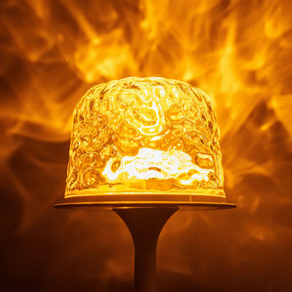 Close-up of witlity skywave lamp's rippled ice-crack glass shade, glowing with warm golden light. The intricate texture is magnified, casting flame-like flowing light patterns against a soft blurred orange background, creating a dreamy cozy atmosphere and highlighting the lamp's unique light art and transparent quality.