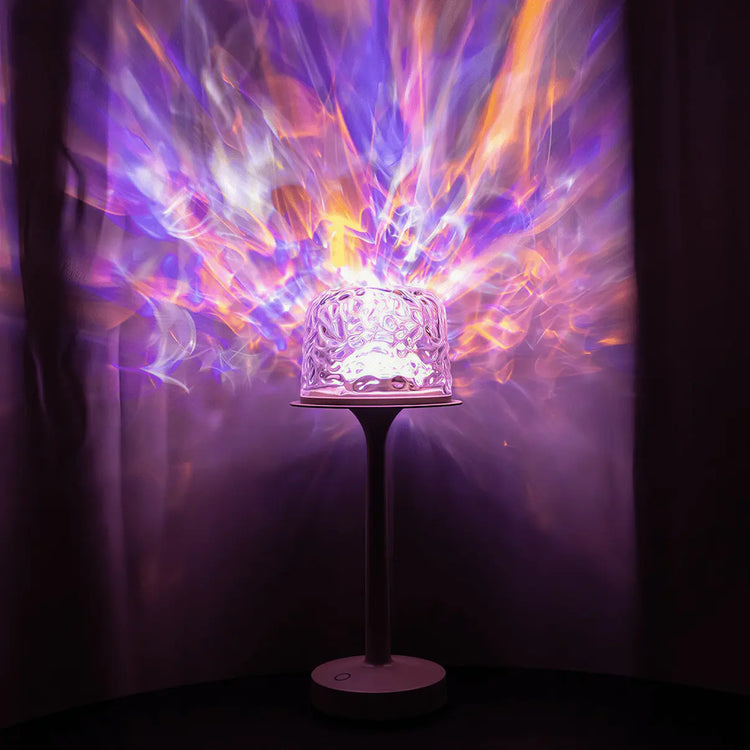 A witlity skywave table lamp with a rippled ice-crack glass shade on a sleek stem casts vibrant multi-colored radial light patterns in purple, orange, and pink hues, resembling flowing auroras against the dark background, showcasing its stunning light effects and enchanting ambiance.